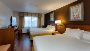A hotel room with two beds, a desk with a television, and a window with curtains. - Vagabond Inn Executive - Green Valley (Green Valley)