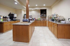 A spacious kitchen with wooden cabinets, a granite countertop, and various appliances including a coffee machine, microwave, and toaster.