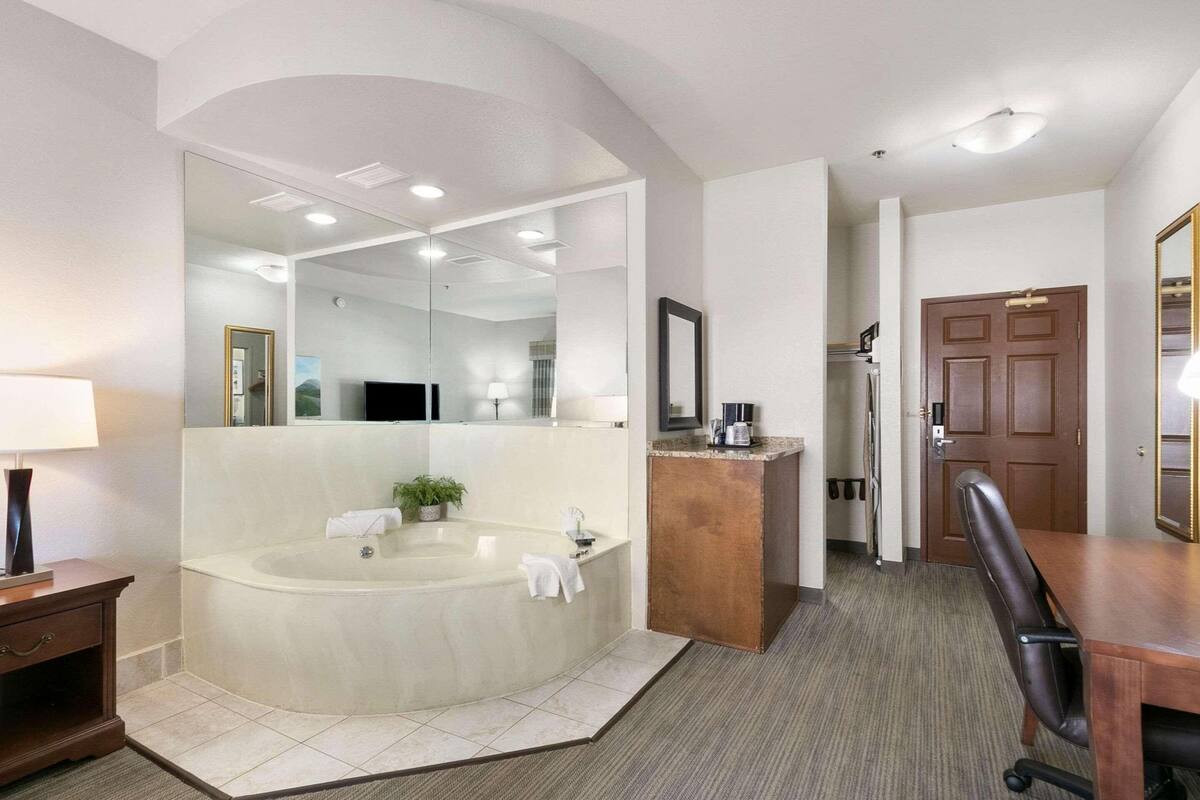 A modern bathroom with a large bathtub, a vanity with a mirror, and a shower area.