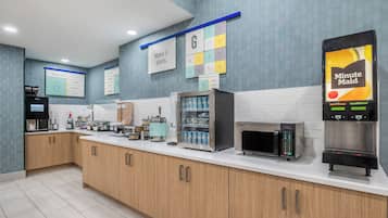 Un área de cocina moderna con cafetera, microondas y refrigerador.