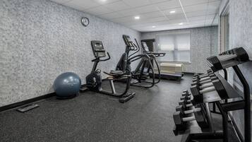 A gym with treadmills, elliptical machines, a stationary bike, a rowing machine, and free weights.