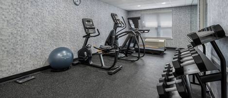 Une salle de sport équipée de tapis de course, d’appareils elliptiques, d’un vélo d’appartement, d’un rameur et de poids libres.
