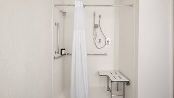 Ein Badezimmer mit Dusche, Toilette und einem kleinen Tisch.