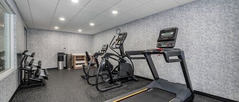 A gym with treadmills, elliptical machines, and a water dispenser.