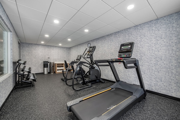 A gym with treadmills, elliptical machines, and a water dispenser.