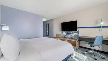 Een hotelkamer met een bed, een bureau, een stoel, een flatscreen televisie en een wandlamp.