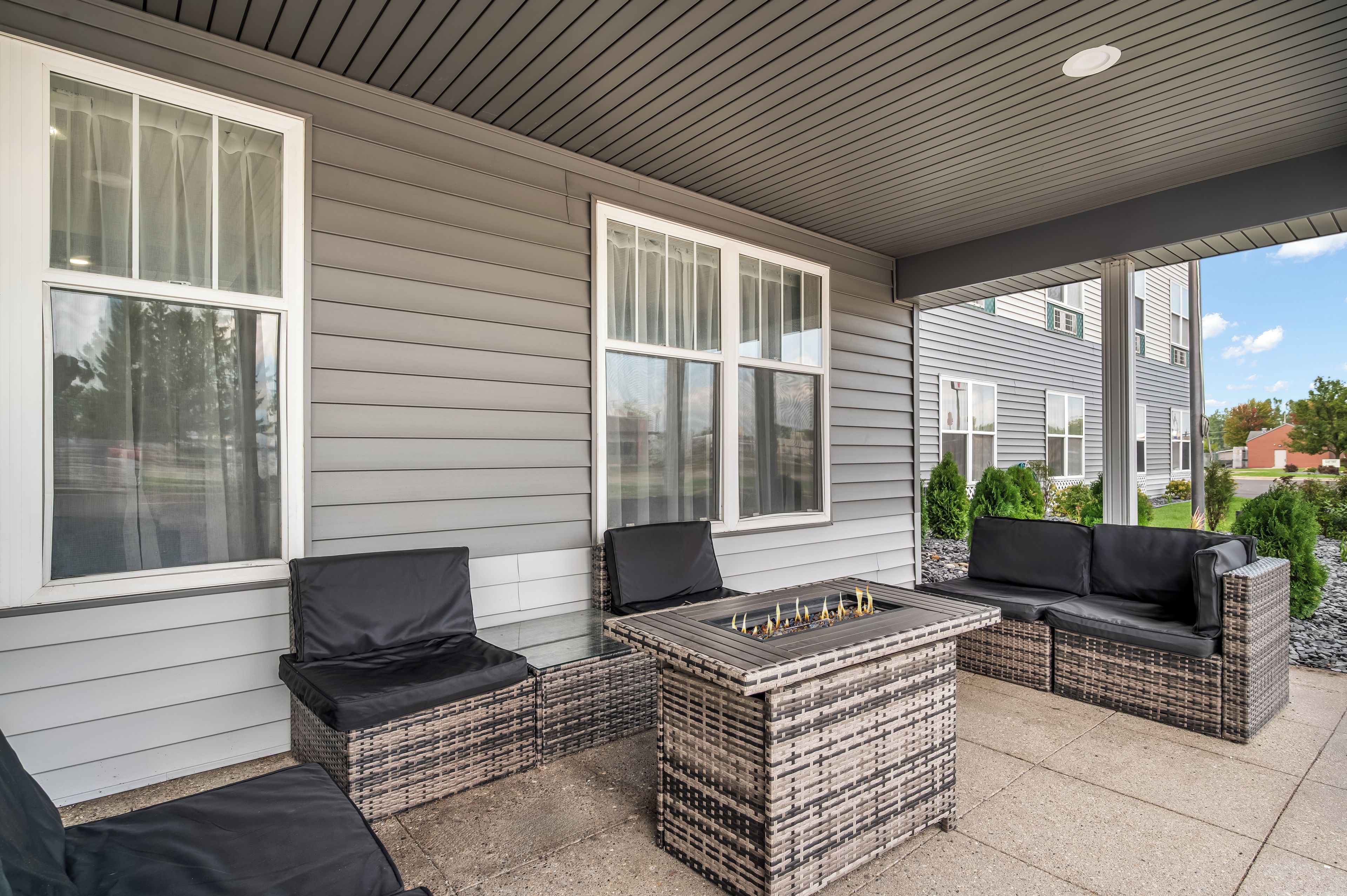 Ein überdachter Patio-Bereich mit Korbmöbeln und einem Feuerkorb.