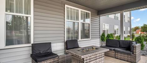 A covered patio area with wicker furniture and a fire feature.