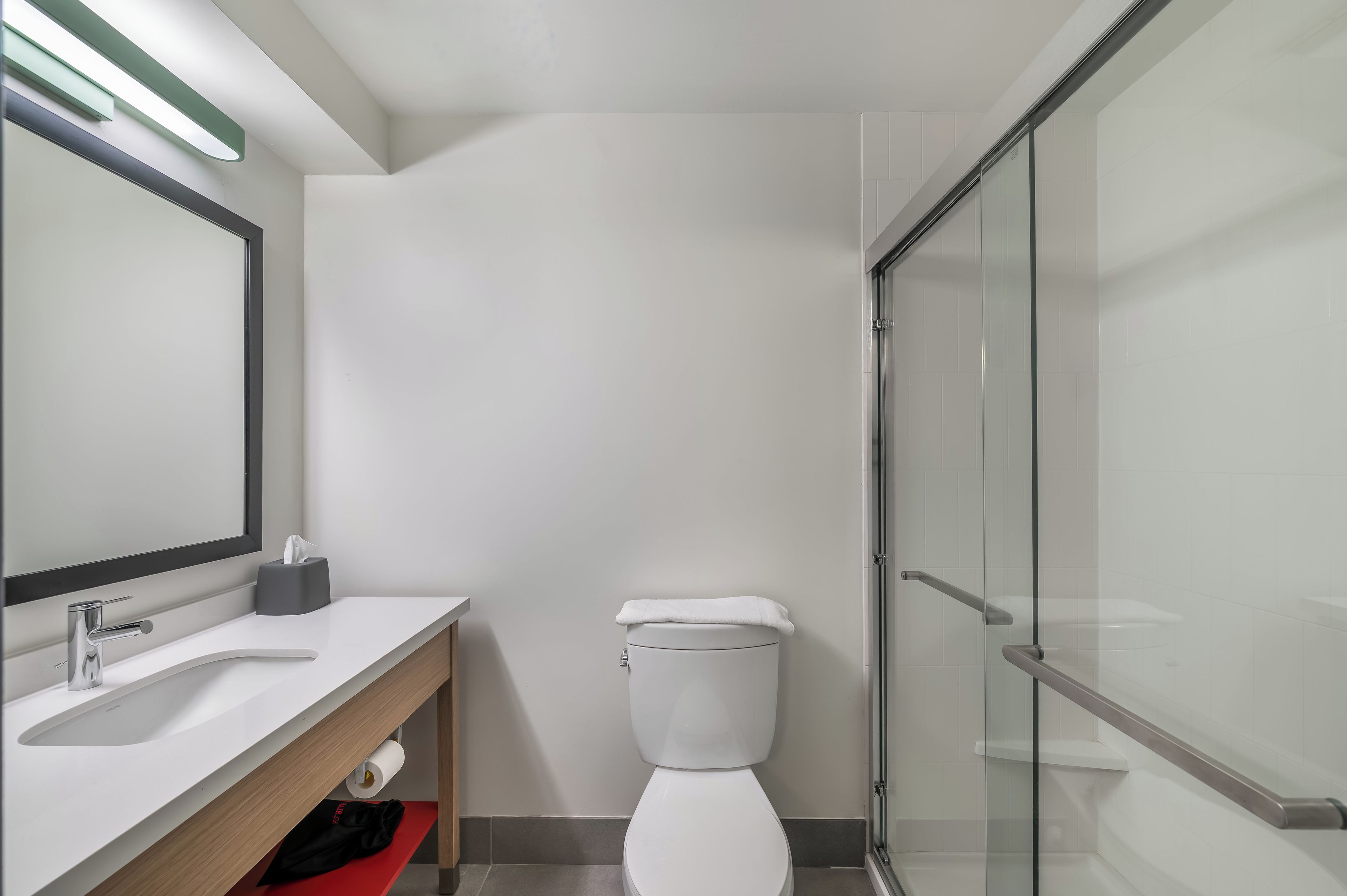 A modern bathroom with a toilet, sink, and glass shower enclosure.
