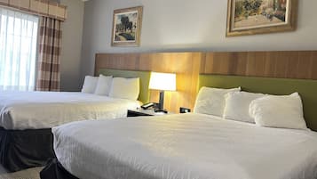 Habitación de hotel con dos camas, una mesita de noche con lámpara y dos cuadros en la pared.