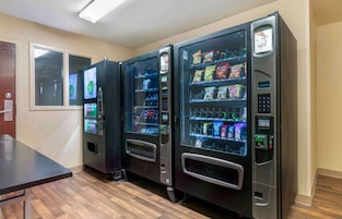 Three vending machines in a room with wooden flooring and a door in the background.