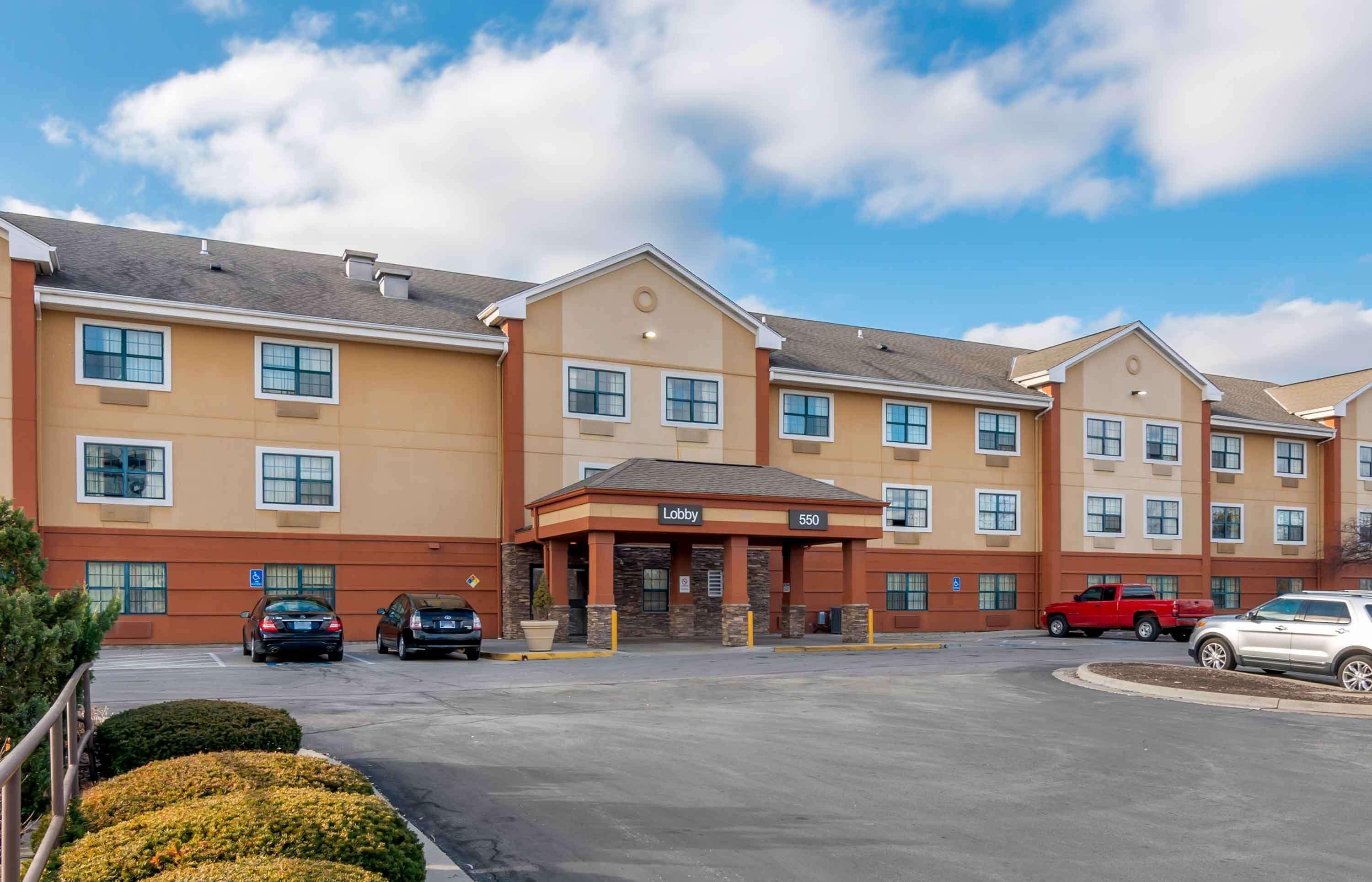 A multi-story hotel with a central lobby, parking lot, and several units with windows.