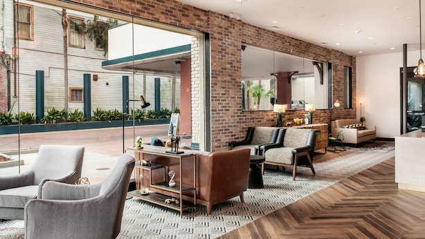 A modern lobby with brick walls, large windows, and a mix of seating areas including sofas and armchairs. - St Charles Coach House, an Ascend Collection Hotel (New Orleans)