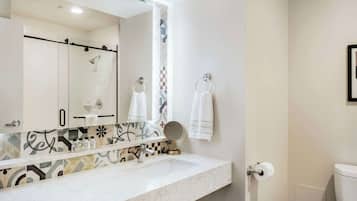 A bathroom with a white sink, a large mirror, a towel rack, and a toilet.