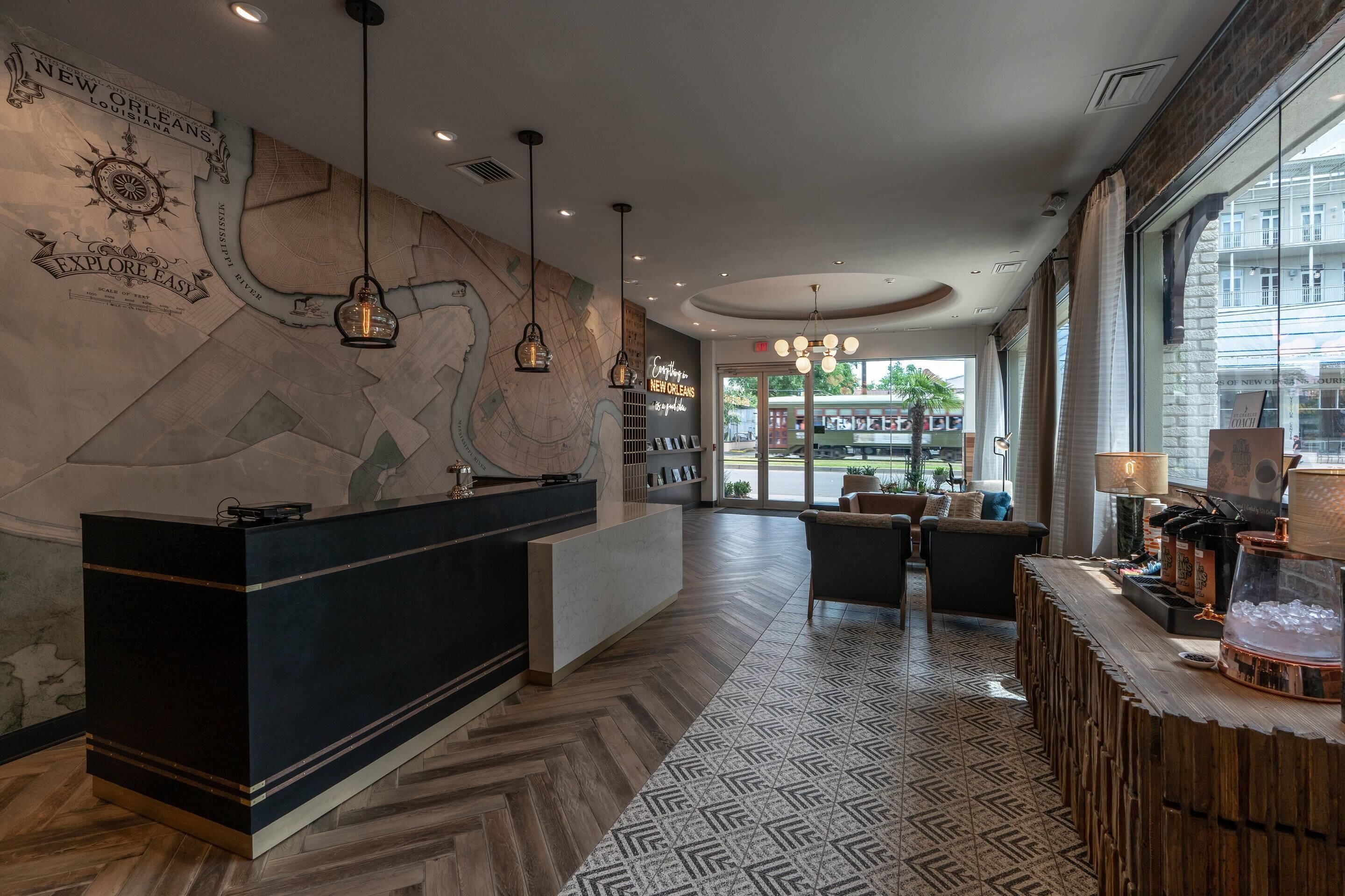 A hotel lobby with a reception desk, patterned flooring, and a large window offering a view of the outside.