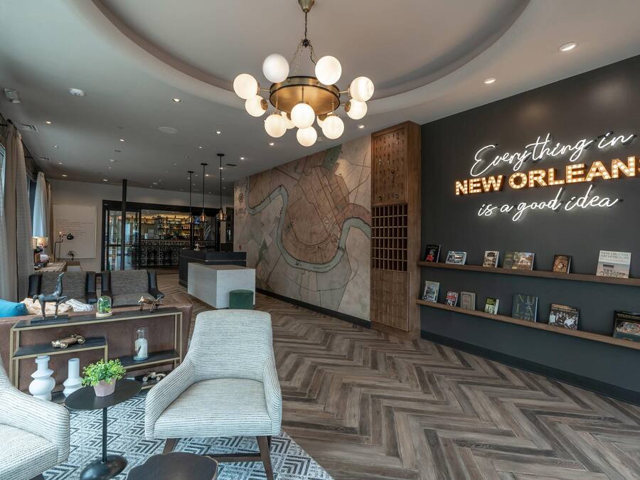 Un hall d’hôtel moderne agrémenté d’une fresque représentant une carte, d’un panneau lumineux au néon et d’une bibliothèque.