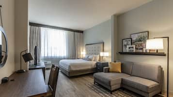 Ein Hotelzimmer mit Bett, Schreibtisch, Sofa und Fernseher.