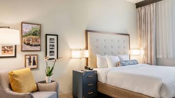 A hotel room with a bed, a chair, a nightstand, and wall art.