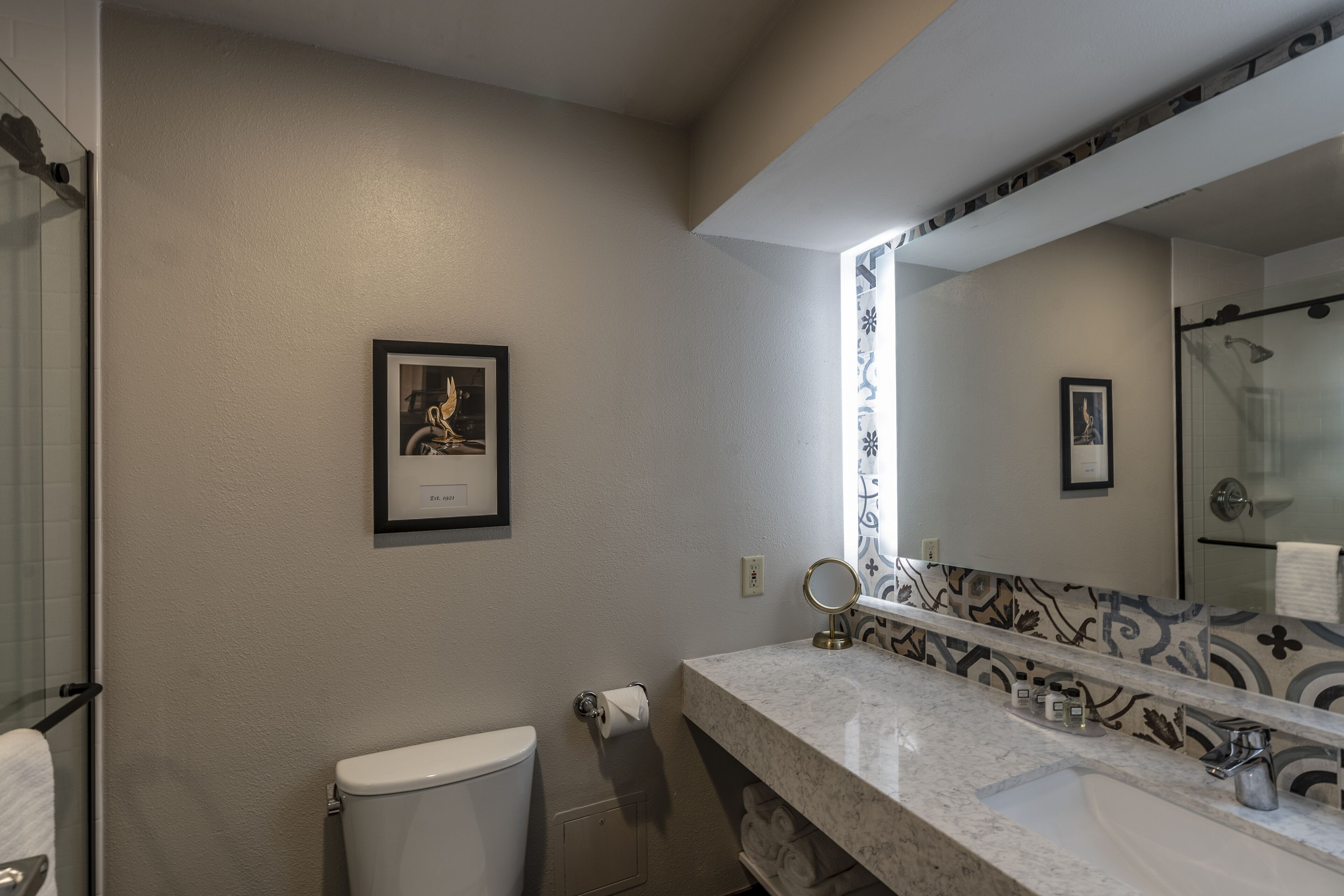 Een badkamer met toilet, wastafel en een grote spiegel.