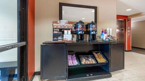 Een hotel receptie met een koffiehoek, plateaus met snacks en een waterdispenser.
