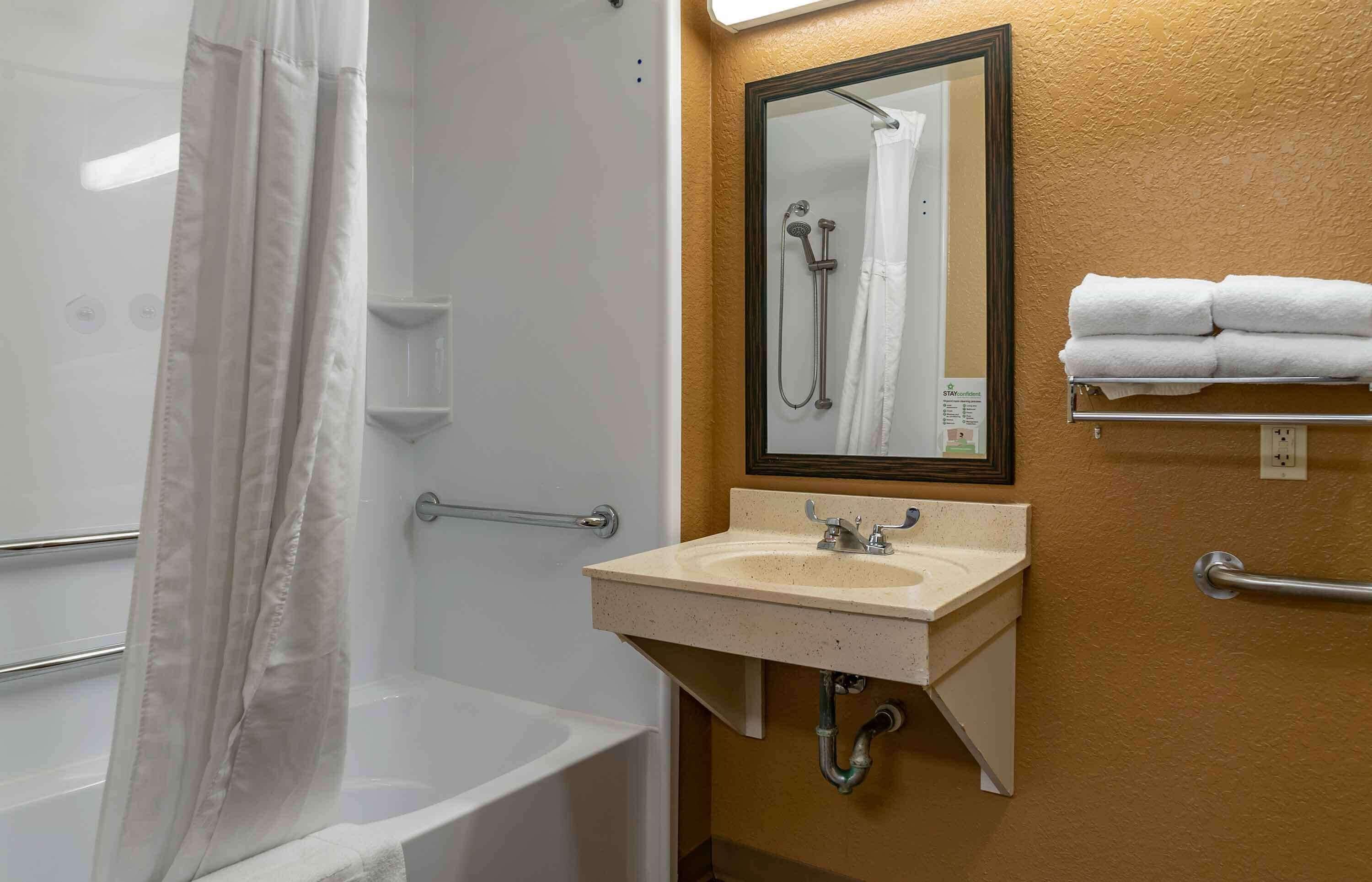 A bathroom with a bathtub, a sink, a mirror, and a towel rack.