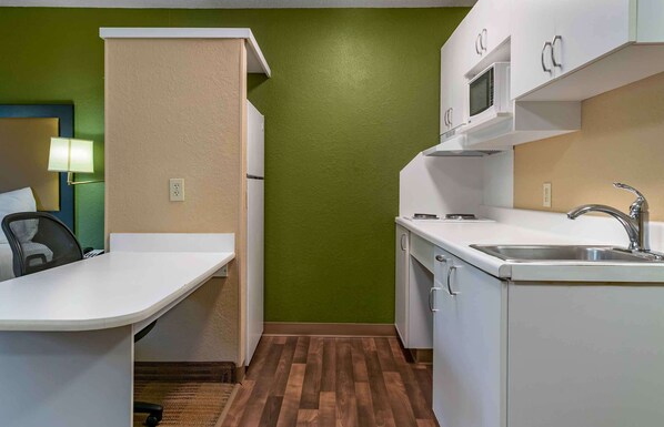 Una kitchenette compacta con microondas, pileta y alacenas.