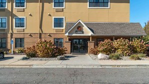 A multi-story hotel with a beige exterior, a lobby entrance, and a parking area.