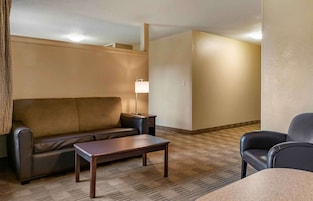 Una habitación de hotel con un sofá, una mesa pequeña, una lámpara y una silla.