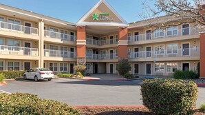 A multi-story hotel with a central lobby, balconies on each floor, and a parking lot in front. - Extended Stay America Suites Sacramento White Rock Rd (Rancho Cordova)