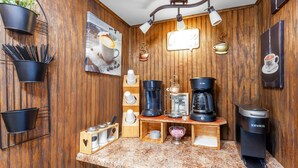 A kitchen with wooden paneling, a coffee machine, and various coffee-related items. - Americas Best Value Inn Brownsville West Tennessee (Brownsville)