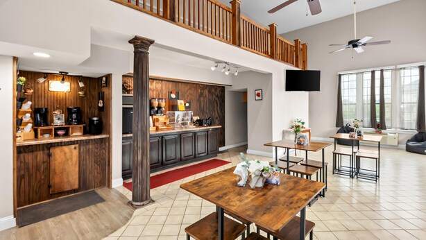 A spacious kitchen with wooden cabinets, a dining area with a large table, and a balcony with a railing. - Americas Best Value Inn Brownsville West Tennessee (Brownsville)