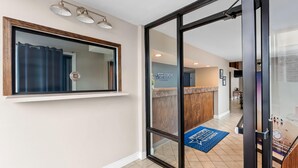 A hotel reception area with a glass door, a reception desk, a blue star-patterned rug, and a sign reading 'AMERICAS BEST VALUE HOTEL.' - Americas Best Value Inn Brownsville West Tennessee (Brownsville)