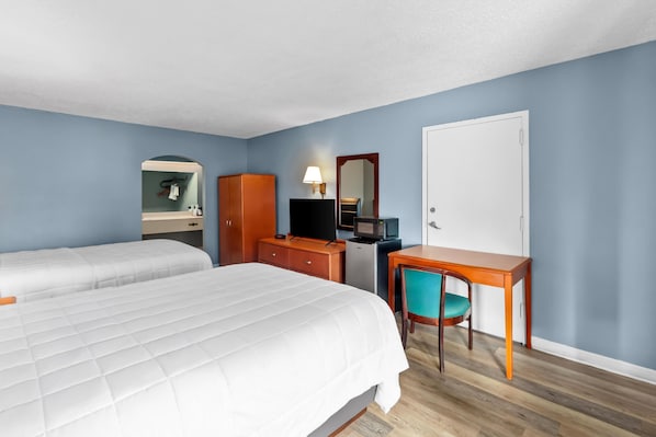 A hotel room with two beds, a desk with a chair, a microwave, a television, and a door. - Americas Best Value Inn Brownsville West Tennessee (Brownsville)