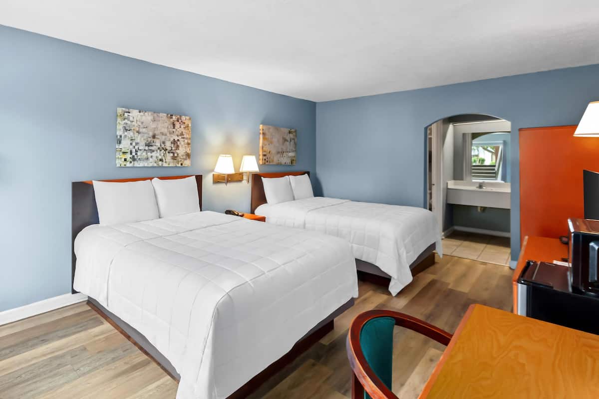 Una habitación de hotel con dos camas, un escritorio y una silla.