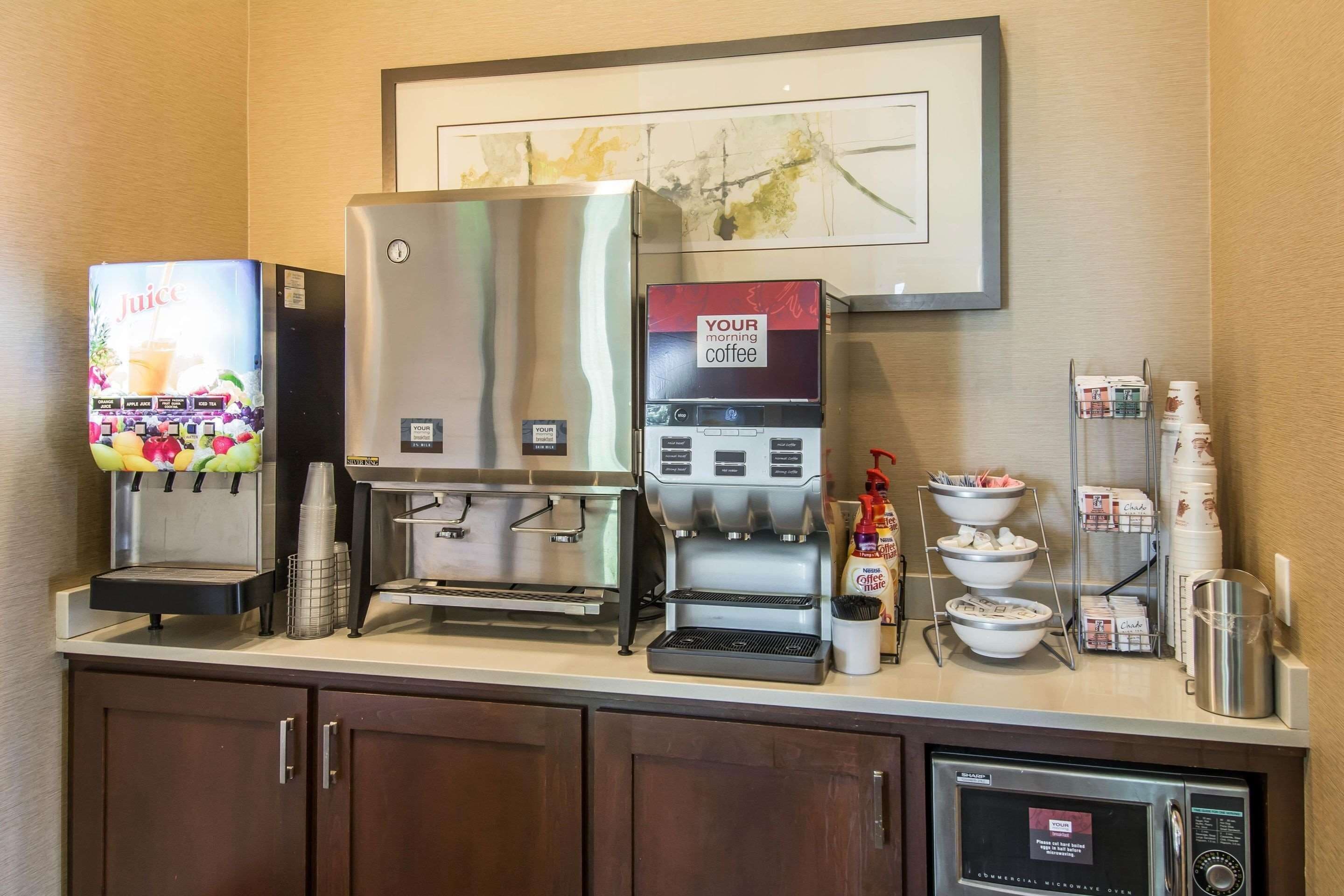 A coffee station with a juice dispenser, a coffee machine, and a microwave.