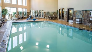 An indoor swimming pool with clear water, surrounded by lounge chairs and tables, large windows, and stone wall accents. - Comfort Inn & Suites Spokane Valley Central (Spokane Valley)