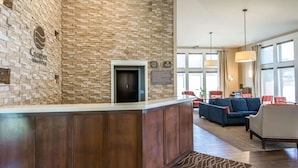 A lobby with a stone wall, a reception desk, a blue sofa, and a large window. - Comfort Inn & Suites Spokane Valley Central (Spokane Valley)