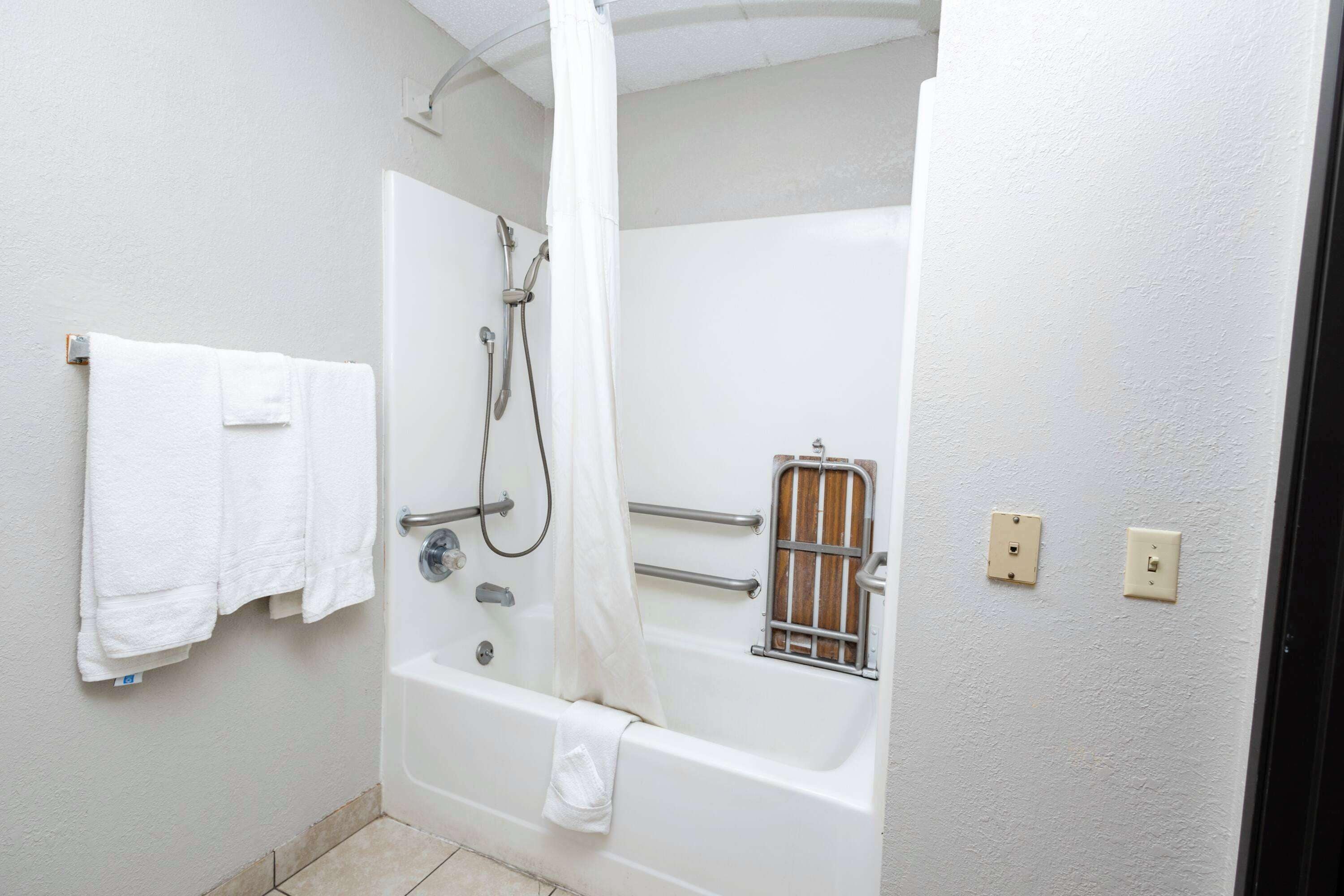 Un baño con bañera, ducha y un toallero blanco.