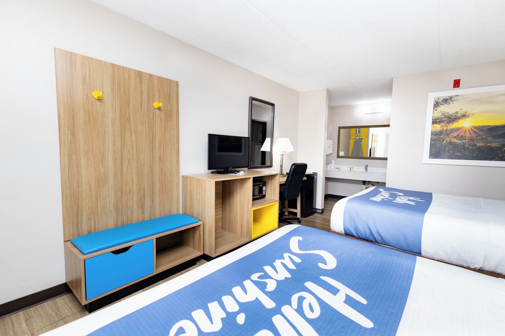 Una habitación de hotel con cama, escritorio, computadora, televisor y armario.