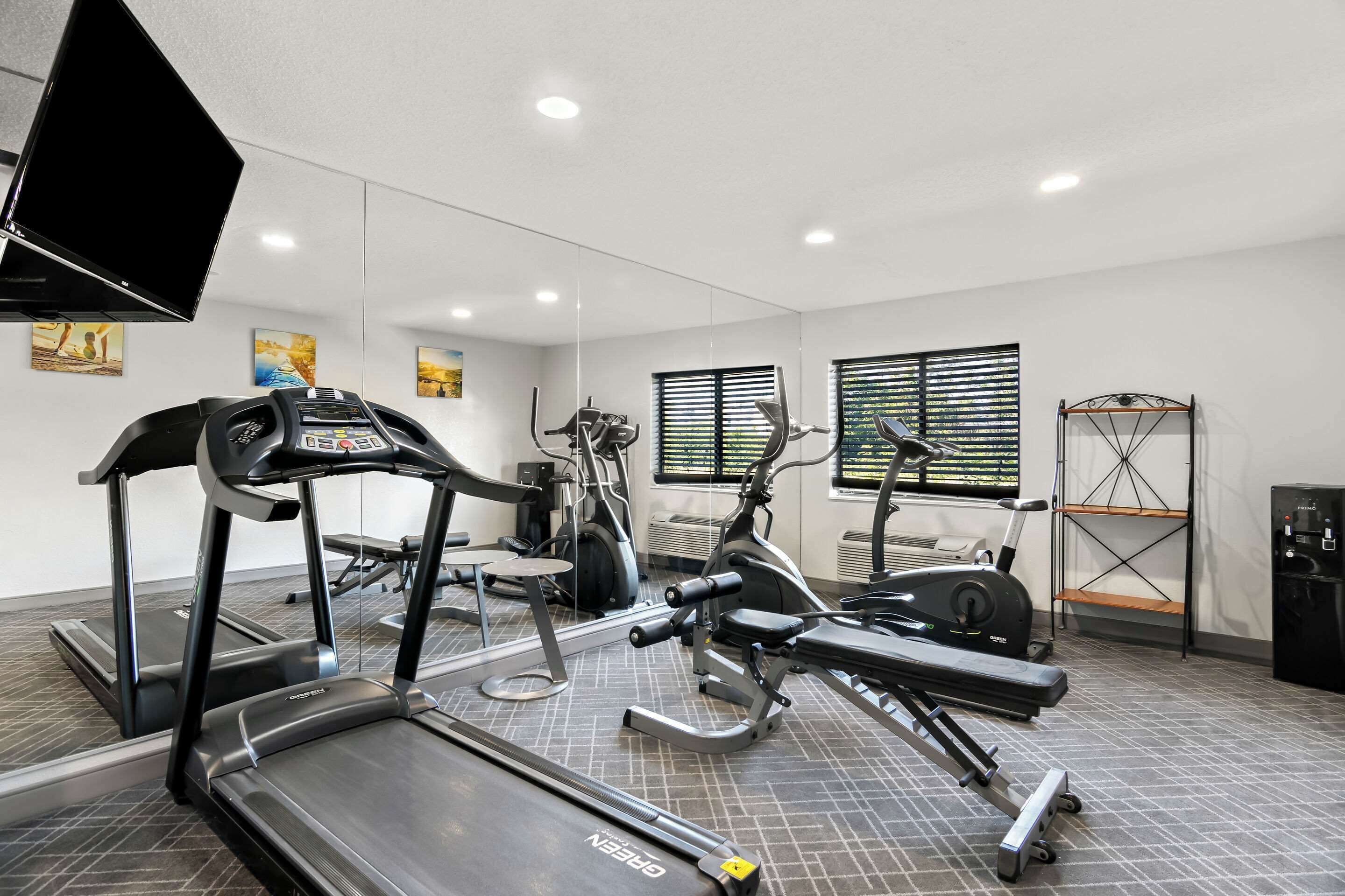 A gym with treadmills, elliptical machines, and weight stations.