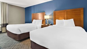 A hotel room with two beds, a nightstand with a lamp, and a window with curtains. - Comfort Inn Joliet West I-80 (Joliet)