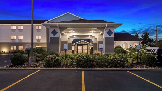A hotel entrance with a covered waiting area, a parking lot, and a building with multiple windows. - Comfort Inn Joliet West I-80 (Joliet)