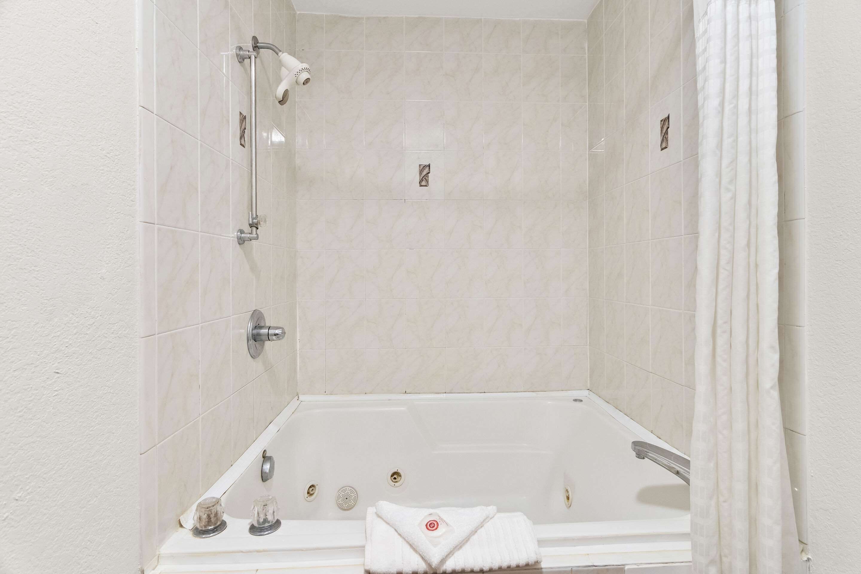 Ein Badezimmer mit einer Badewanne, einer Duschbrause und einem Handtuchhalter.