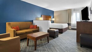 A hotel room with a blue accent wall, a sofa, a bed, a TV, and a small table. - Comfort Inn Joliet West I-80 (Joliet)
