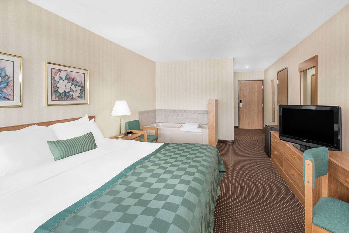 A hotel room with a bed, a desk, a television, and a bathroom.
