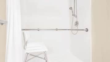 Una bañera blanca con ducha y barra de apoyo.