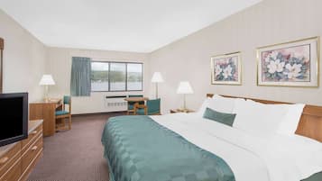 Ein Hotelzimmer mit einem großen Bett, einem Schreibtisch, einem Sessel, einem Fernseher und einem Fenster mit Blick ins Freie.