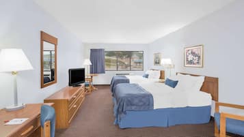 Quarto de hotel com duas camas, uma escrivaninha, televisão e janela com vista.