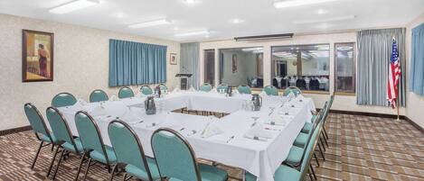 Ein Konferenzraum mit einem langen Tisch, Sitzgelegenheiten in Türkis und einem gemusterten Teppich.