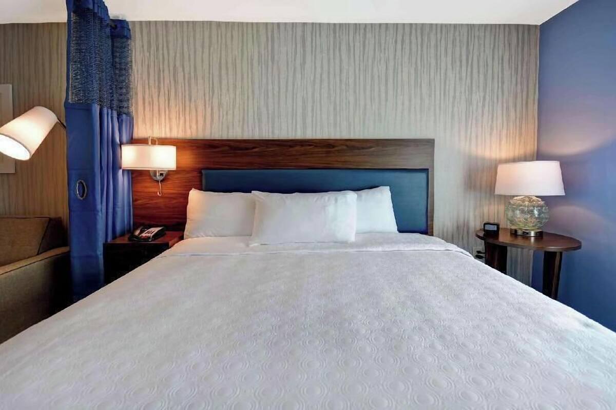 A hotel room with a large bed, two bedside tables, a nightstand, and a headboard.